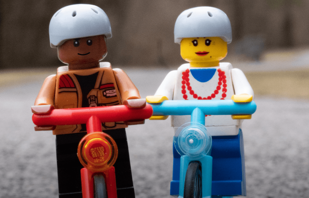 Two Lego figurines on scooters wearing helmets