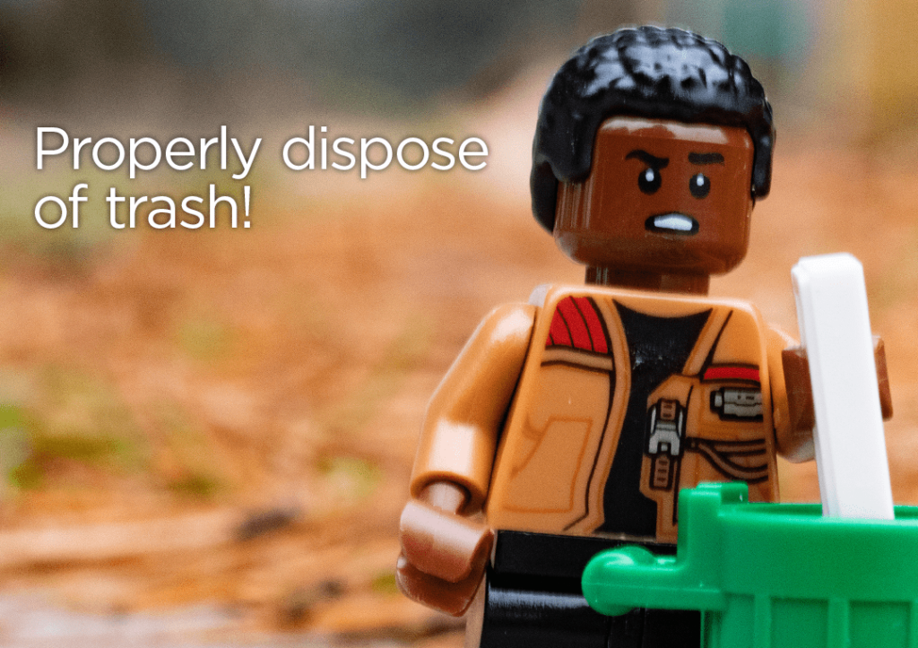 Lego figure throwing away litter into a trash can with text: " Properly dispose of trash!"